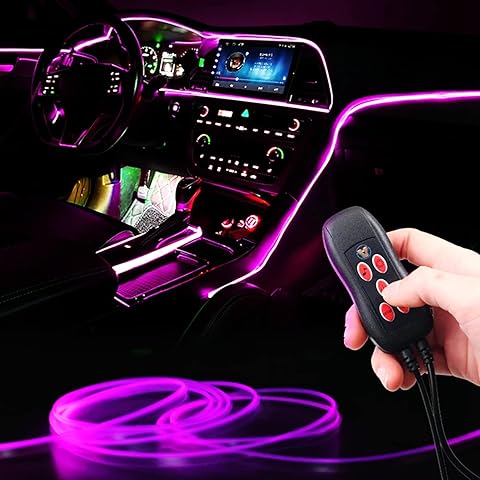 Car interior with pink LED strip lights and a hand holding a remote control.