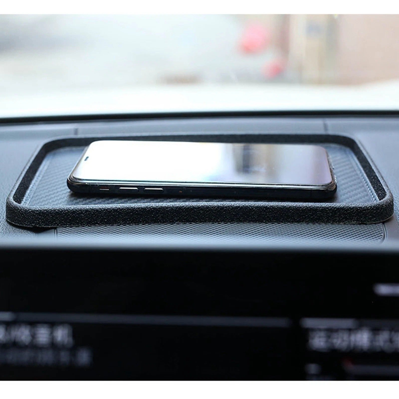 Phone on a black car dashboard pad with blurred background