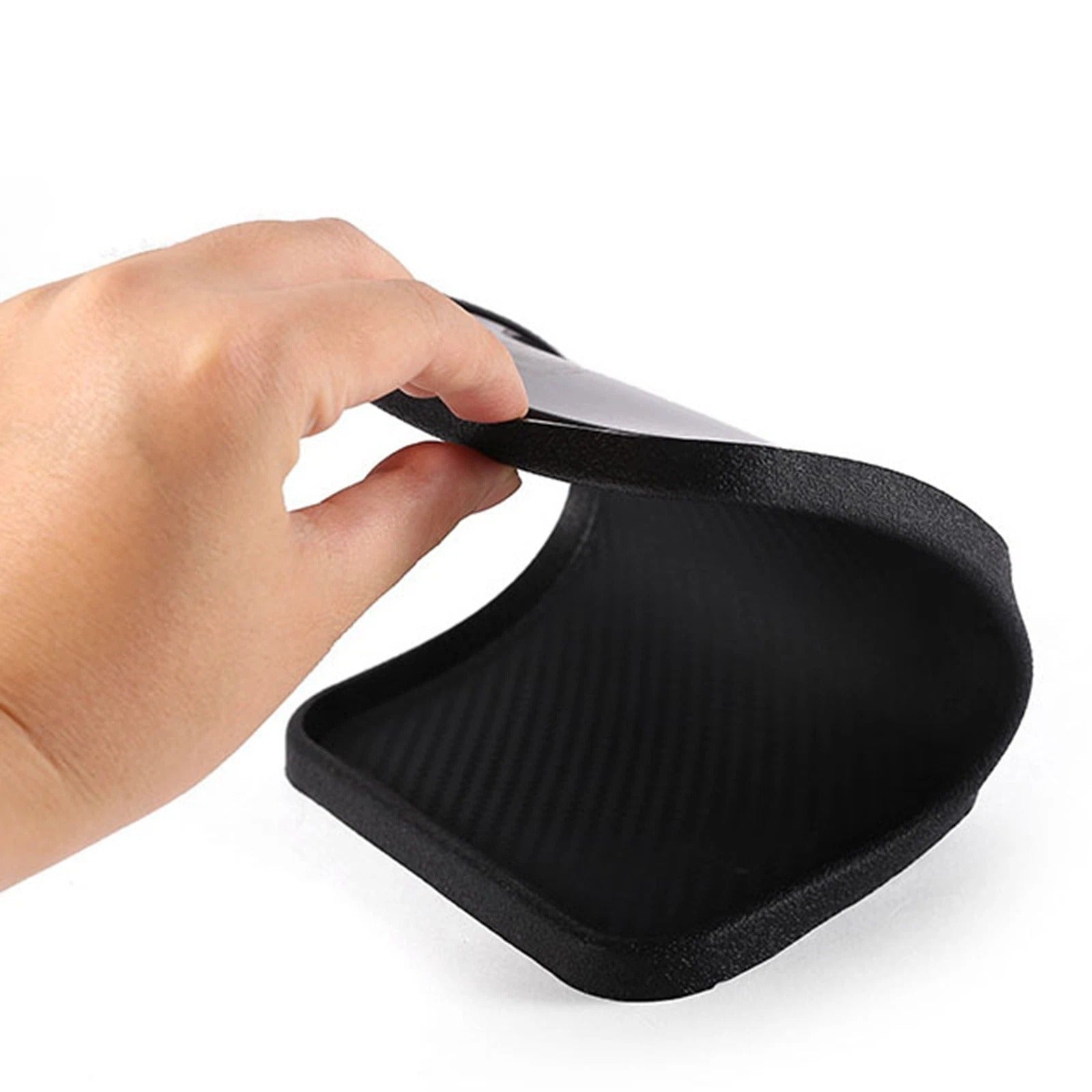 Black silicone mat held by a hand on a white background